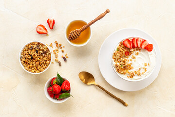 Bowl with yogurt and oatmeal served with honey and strawberry, top view