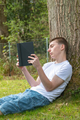 Obraz premium Teenage Boy Reading Outdoors