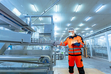 Workers in safety gear inside a factory check equipment and products on production and...