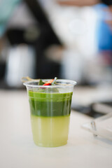 Close up and selective focus a take-out iced matcha lemon with herb at cafe