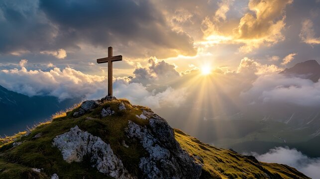 crucifix at the top of a mountain with sunlight breaking through the clouds inspirational christian image