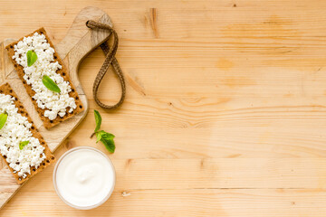 Crispy toasts with farm cottage cheese on wooden board, top view