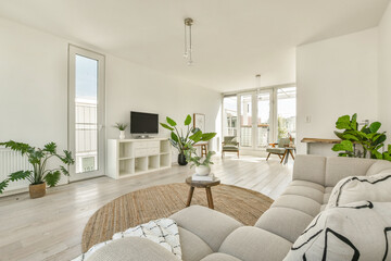 Fototapeta premium A spacious, modern living room featuring a light color palette, stylish furniture, and indoor plants, creating a serene atmosphere for relaxation.