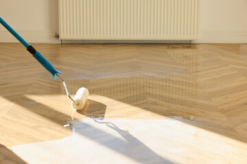 Polishing parquet with roller and varnish indoors, closeup. Space for text