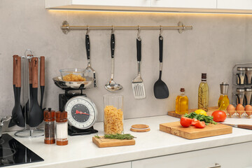Retro mechanical kitchen scale, other utensils and different food products on white marble...