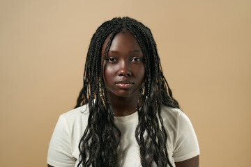 Young black woman posing with long braided hair on beige background