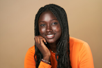 Young black woman with braids smiling and resting chin on hand