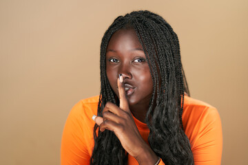 Young woman holding finger on lips making silence gesture