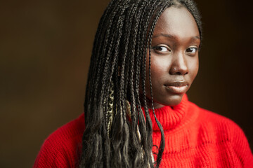 Young black woman posing with long braided hair and red sweater