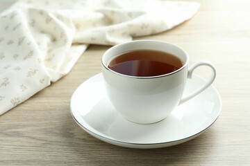 Aromatic tea in cup on wooden table, closeup