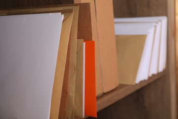 Different paper envelopes and parcels on wooden shelf in post office, closeup