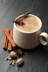 Aromatic Masala tea in cup and spices on black table, closeup