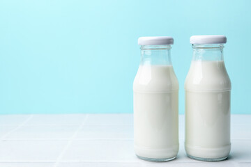 Fresh milk on white table against light blue background. Space for text