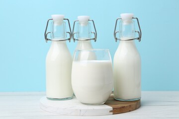 Fresh milk on white wooden table against light blue background