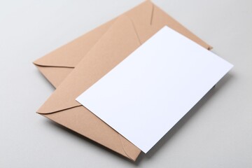 Blank greeting card and paper envelopes on light background, closeup
