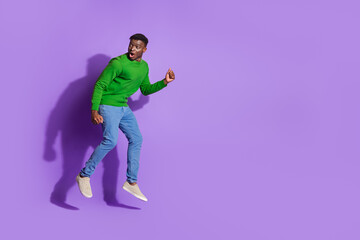 Young fashionable man in vibrant casual attire jumping playfully against a bold purple background, exuding energy and modern style.