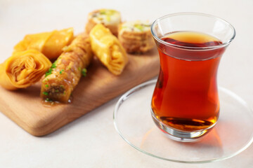 Traditional Turkish tea in glass cup and fresh baklava on white table, closeup