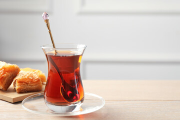 Tasty Turkish tea served with baklava on wooden table. Space for text