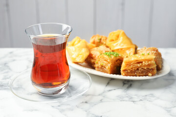 Tasty Turkish tea served with baklava on white marble table