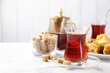 Tasty Turkish tea served with sweets on white marble table. Space for text