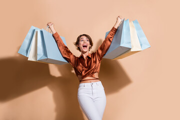 Photo of sweet impressed lady dressed brown top rising shoppers looking empty space isolated beige color background