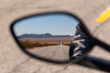 Lonely desert road in motorcycle rear view mirror highway desolate isolated arid two lane 
