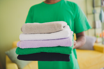 Cropped photo of nice young man hold towels wear t-shirt modern green interior apartment indoors