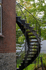 The exterior corner of a vintage brownstone with brown bricks and a grey foundation. The antique...