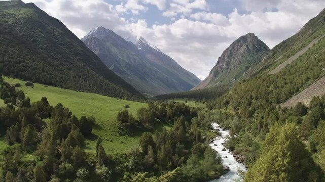 4K aerial footage showcases a mountain river running through the lush valleys of Ala Archa National Park in Kyrgyzstan, surrounded by alpine scenery.