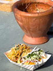 A traditional terra cotta orange colored hot pot with remnants of a Thai dish along the inside of...