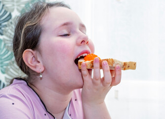 A 9-year-old Caucasian girl eats a sandwich with red caviar with appetite.