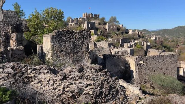 Crumbling stone houses dot the hillside of Kayakoy, an abandoned ghost town near Oludeniz, Fethiye, T&uuml;rkiye, echoing its Greek heritage and tragic 20th-century exodus.