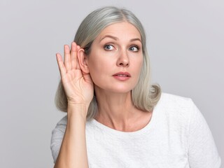 Fototapeta premium old pretty woman looking serious and curious, listening, trying to hear a secret conversation or gossip, eavesdropping