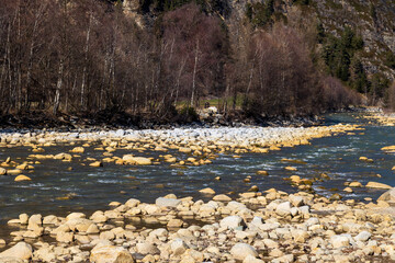 Mountain river with rocky banks and early spring trees, alpine landscape, Ötztal, Austria..