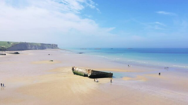 A fragment of the artificial port adorns the beach of Arromanches-les-Bains, in Europe, France, Normandy, Calvados, in summer, on a sunny day.&nbsp;