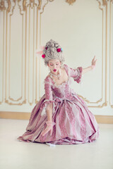 Fototapeta premium Elegantly dressed woman in ornate pink gown reminiscent of historical royalty, gracefully poses within a beautifully decorated interior