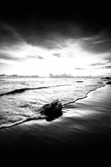 Black and white photo of a bridge over the sea at sunset.