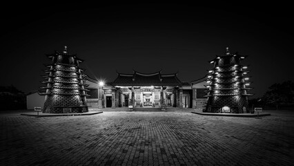 Black and white photo of a bridge over the sea at sunset.