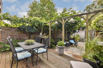 Obraz premium This garden patio features stylish furniture surrounded by vibrant plants and trees, creating a peaceful and inviting outdoor space.