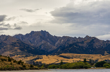 Lake Wanaka, a summer cloudy afternoon with a mountain range and the town of Wanaka on the shore. South Island, New Zealand