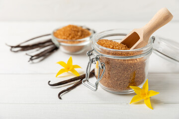 Aromatic vanilla sugar. Vanilla pods. Vanilla sticks, brown and white sugar in a bowl on a textured background. Vanilla flowers, spices and herbs for desserts and baking. Space for text. Copy space