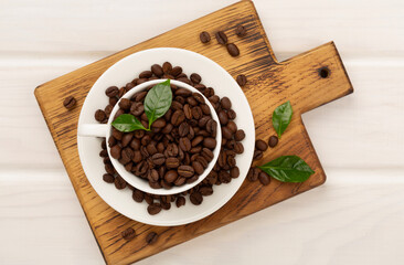 Roasted coffee beans with leaves on wooden background,top view