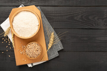 Bowl with spelt flour on wooden background, top view