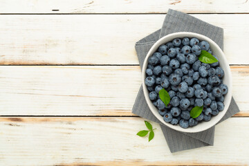 Bowl with fresh bright blueberries on wooden background,top view