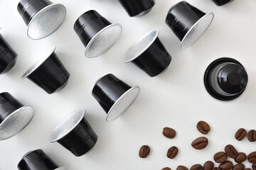 Espresso coffee capsules in rows and beans on white table