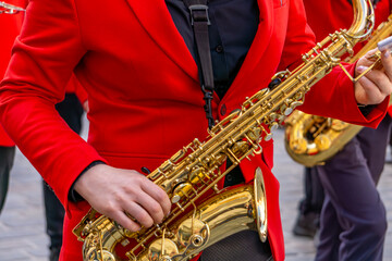 Naklejka premium musician in a red suit plays the saxophone during a street performance. Other musicians in similar outfits are visible in the background