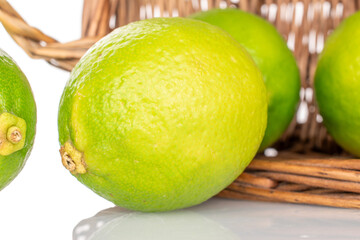Several juicy limes in a basket isolated on a white background, close-up.