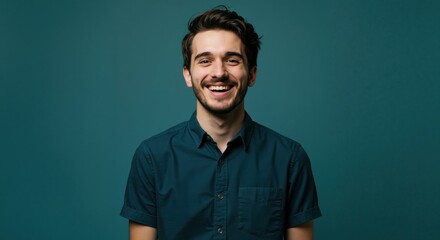 Smiling young man posing against a teal background  