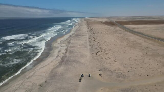 Drone flying over Skeleton Coast with ocean waves on a sunny day with blue sky