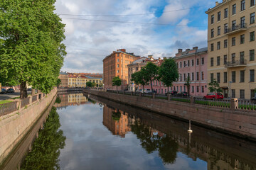 View of a residential building in the shape of an iron on the embankment of the Griboyedov Canal on a sunny day, St. Petersburg, Russia